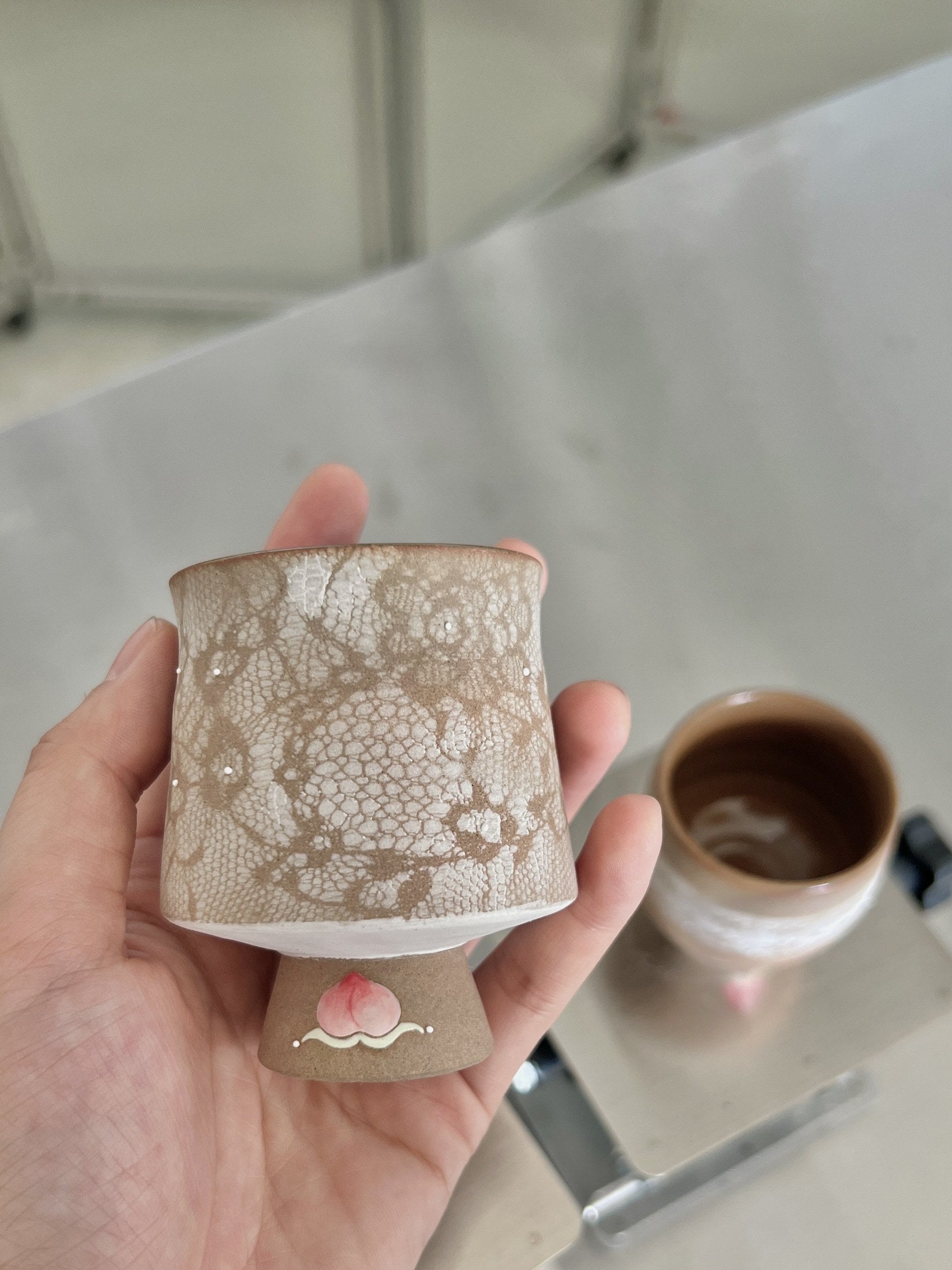 Lace-patterned ceramic cup held in a hand, archive 062